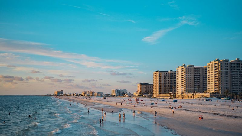 Clearwater Beach shoreline at golden hour with beachfront hotel towers and swimmers