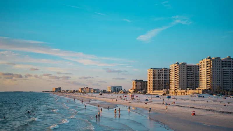 Clearwater Beach shoreline at golden hour with beachfront hotel towers and swimmers